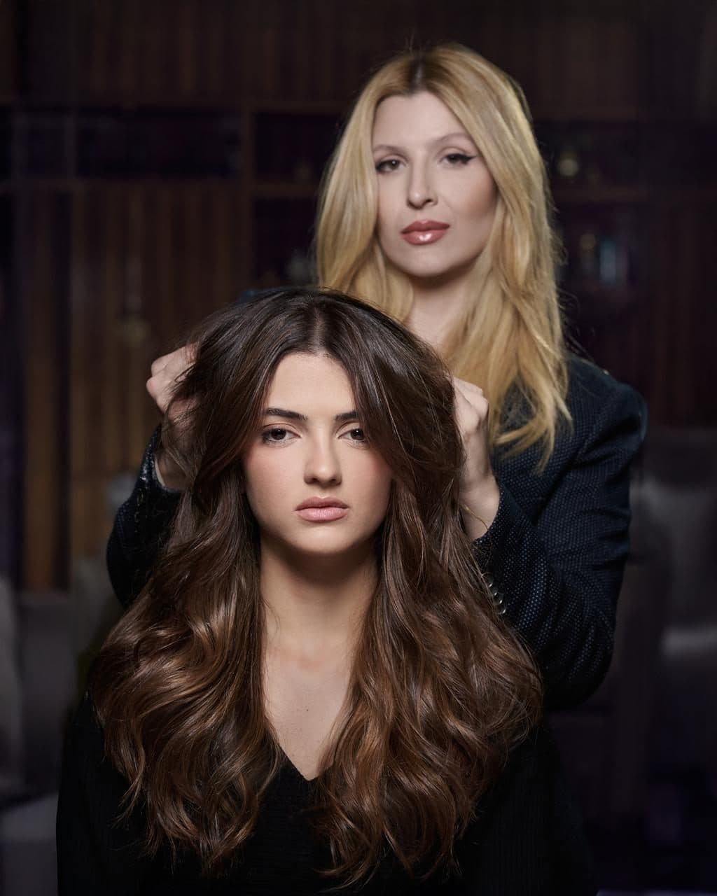 Duas clientes com escova modelada, uma loira e uma morena, no salão